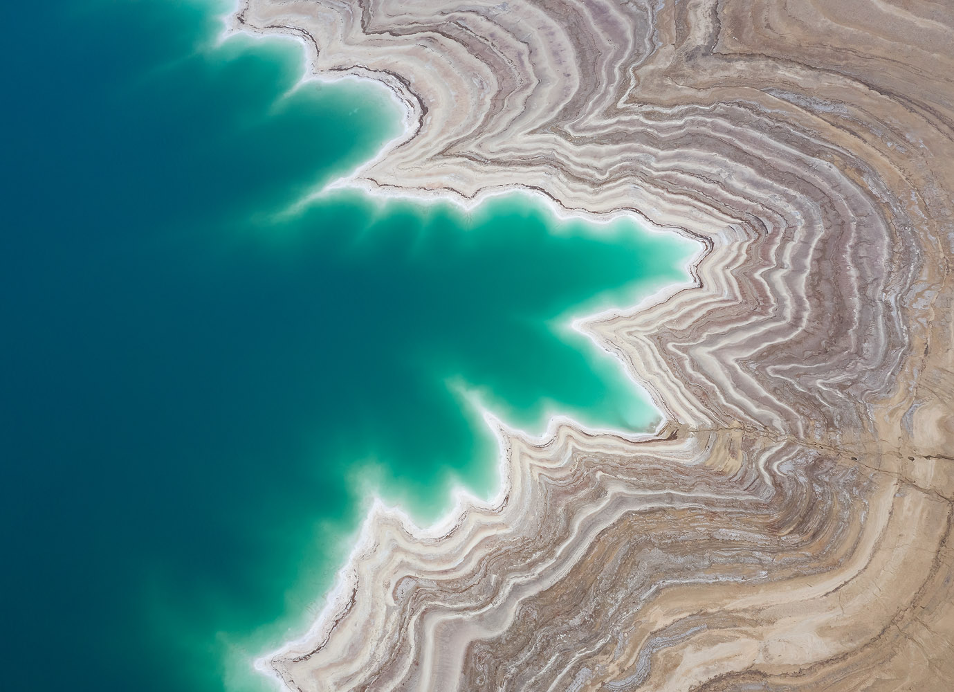 An aerial perspective exposes the beautiful contour and layers of the shore of the Dead Sea.