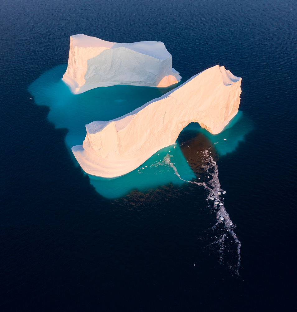 A gigantic iceberg floating in Disko Bay, Greenland. The position of the iceberg meant it was impossible to get separation of its two parts when still showing the light passing through the arch and hitting the back segment from the water level. Another clear advantage is the fact that the submerged part of the iceberg is beautifully showing, in addition to debris from a recent collapse in the arch.