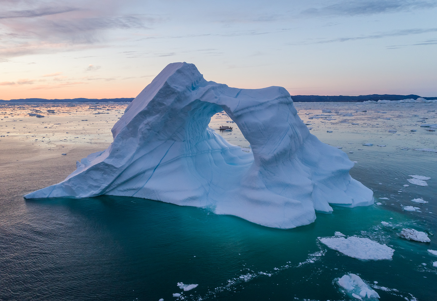 The window of showing the boat in the middle of the arch was very small. Delicate movements of the drone allowed me to get the shot with ease. </br>DJI Phantom 4 Pro, 1/40 sec, F5.6, ISO 200. Disko Bay, Greenland