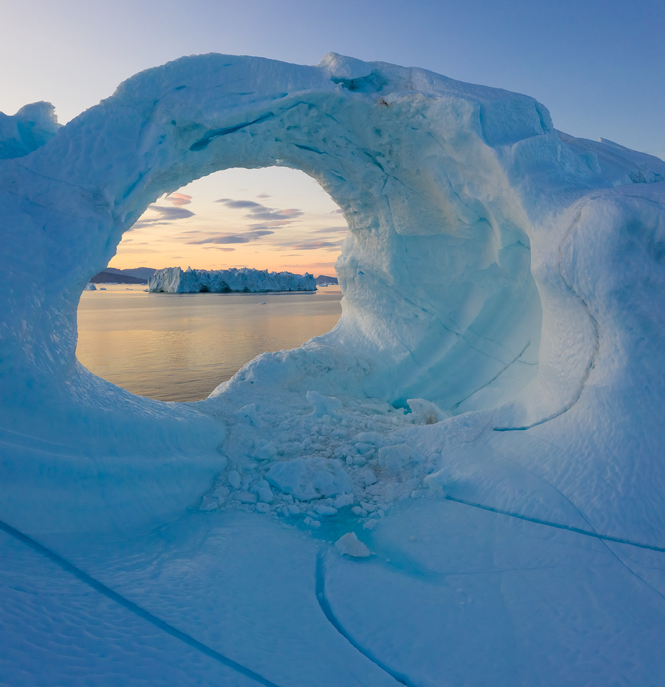 To get the composition I wanted with the faraway iceberg and lenticular clouds framed inside the hole in the closer iceberg, I had to get very close to the ice. Needless to say, this would have been impossible in any other way, as I wouldn't step on this iceberg, and no manned aircraft would fly this close to it. </br>DJI Mavic II Pro, 1/30 sec, f/8, ISO 200, vertical stitch. Uummannaq, Greenland