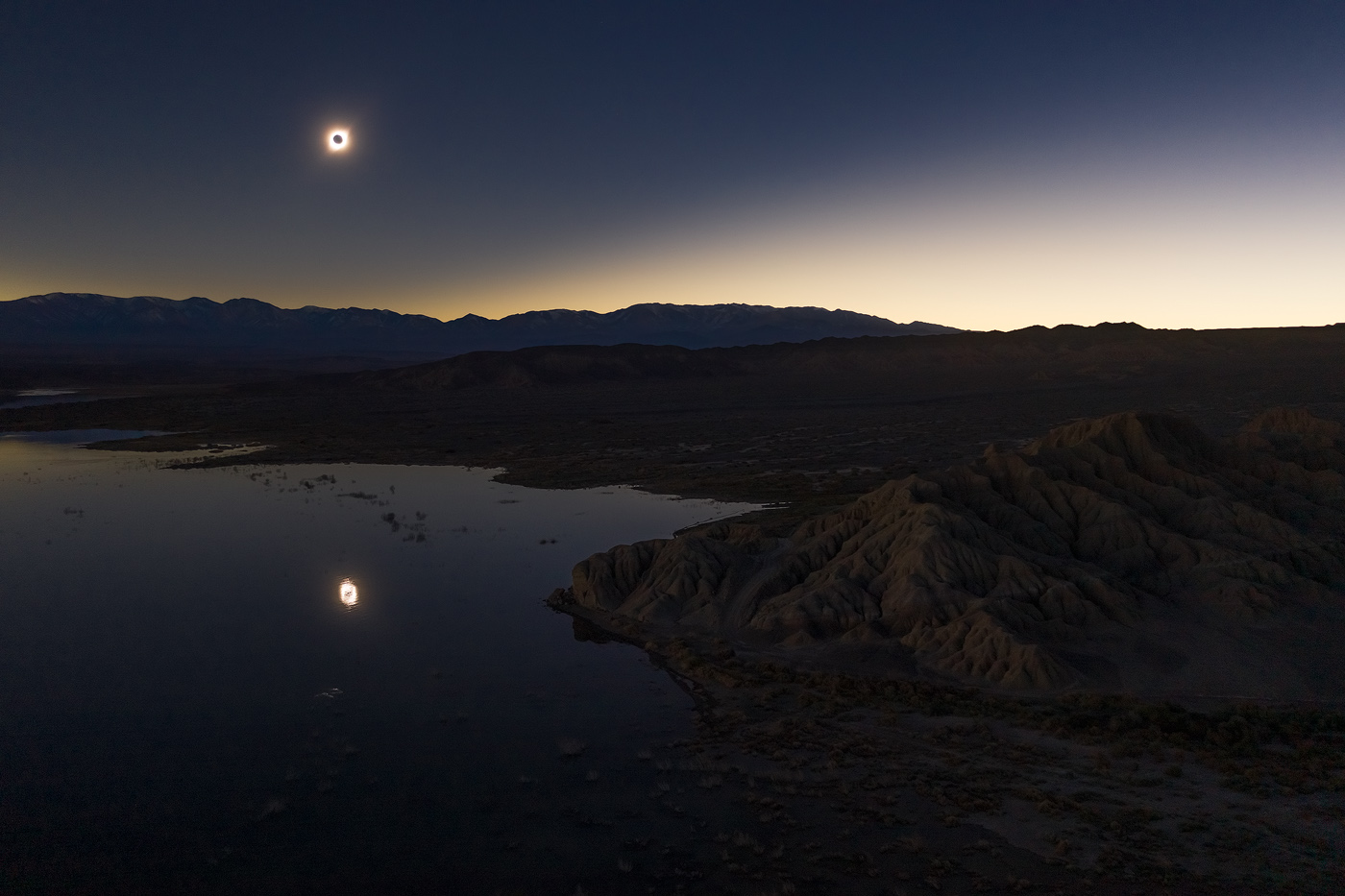 A very original shot: a total solar eclipse low in the sky, reflecting in a lake.<br>DJI Mavic II Pro, f/2.8, 1/10 sec, ISO 100 <br>Lago Cuesta del Viento, San Juan province, Argentina