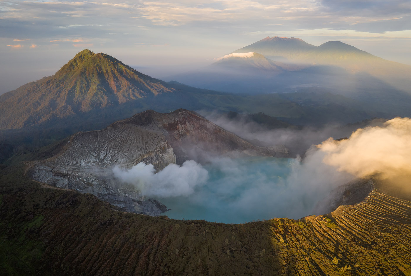Five volcanoes in the Ijen complex: The Bottom of the frame is filled with Ijen crater. To its left, the lush, green Gunung Ranti. then farther away, from left to right: Pendil, Raung and Suket. The shadow from the bottom-left to the mid-right is cast by Gunung Merapi, just behind me.